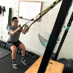 person performing a squat with the suspension trainer